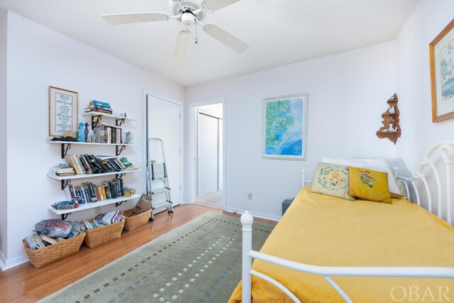 bedroom featuring a ceiling fan, baseboards, and wood finished floors