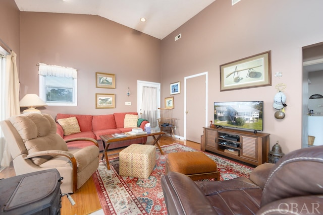 living room featuring high vaulted ceiling, visible vents, and light wood-style flooring