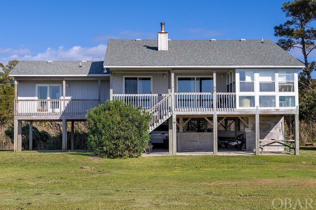 rear view of property featuring a patio, a shingled roof, a yard, stairway, and a chimney