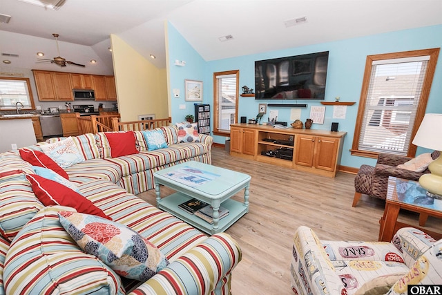 living area featuring light wood-style floors, visible vents, and vaulted ceiling