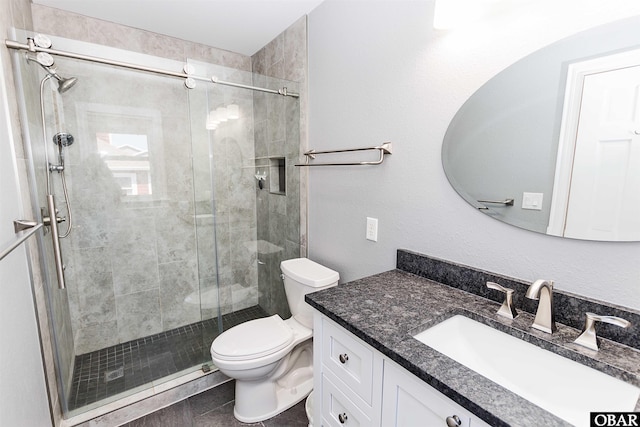 bathroom featuring toilet, a shower stall, and vanity