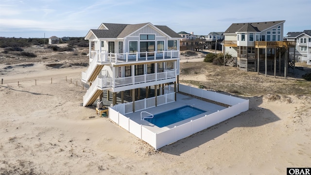 rear view of property with a fenced backyard, a residential view, a fenced in pool, a balcony, and stairs