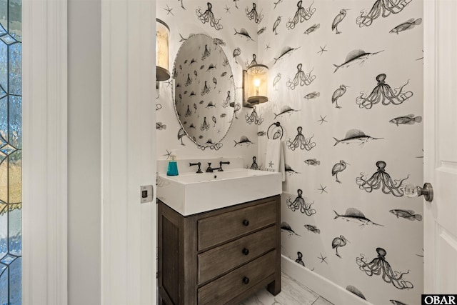 bathroom with baseboards, vanity, and wallpapered walls