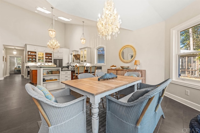 dining space with an inviting chandelier, baseboards, and high vaulted ceiling