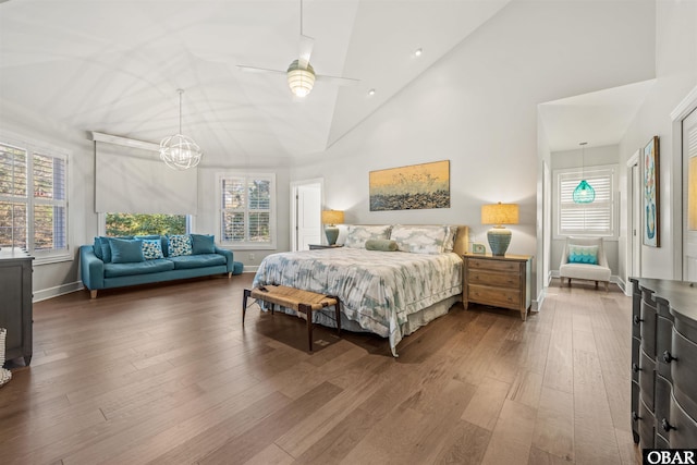 bedroom with high vaulted ceiling, baseboards, and wood finished floors