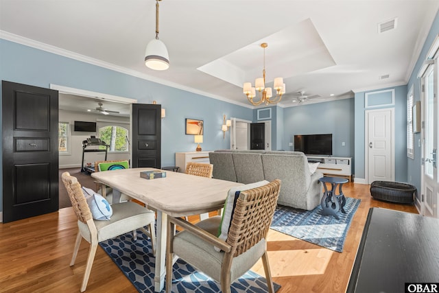 dining area with light wood finished floors, ornamental molding, ceiling fan with notable chandelier, and visible vents