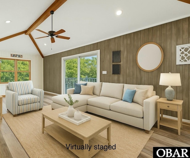 living area with wood walls, ceiling fan, light wood-type flooring, and vaulted ceiling with beams