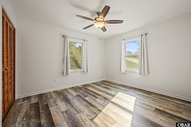 unfurnished bedroom with a closet, multiple windows, and wood finished floors