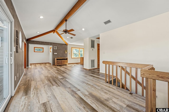 hallway with visible vents, vaulted ceiling with beams, wood finished floors, and baseboards
