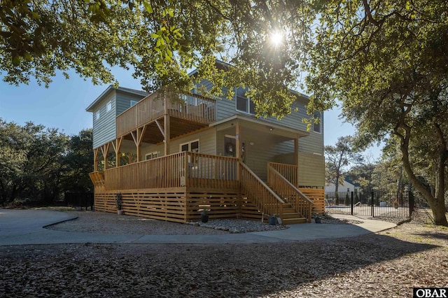 rear view of house with covered porch, fence, a balcony, and stairs