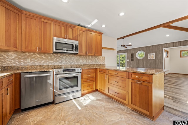 kitchen featuring a ceiling fan, stainless steel appliances, decorative backsplash, and a peninsula