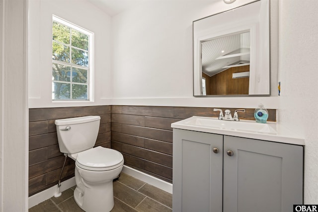 half bath featuring vanity, toilet, and wainscoting