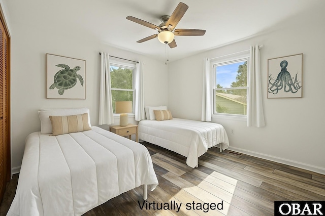 bedroom with wood finished floors, ceiling fan, visible vents, and baseboards