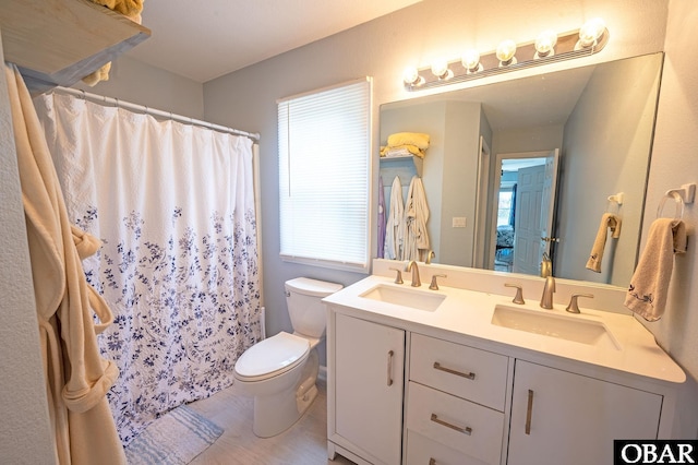 full bath with toilet, a shower with curtain, double vanity, and a sink