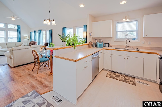 kitchen featuring visible vents, stainless steel dishwasher, open floor plan, a sink, and a peninsula