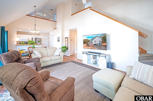 living room featuring a chandelier, high vaulted ceiling, baseboards, stairs, and light wood-type flooring