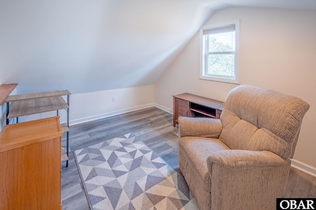 living area featuring vaulted ceiling, wood finished floors, and baseboards