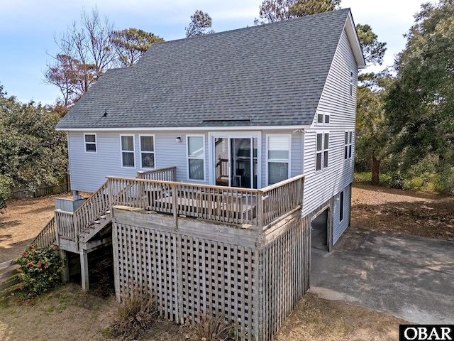 rear view of property featuring a shingled roof and a wooden deck