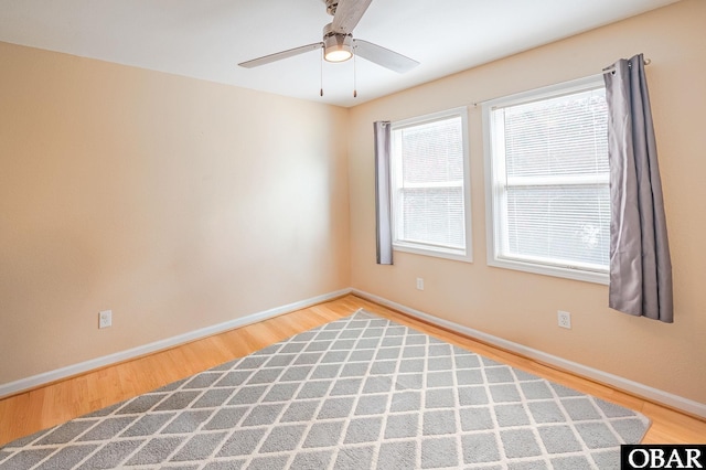 spare room featuring a ceiling fan, baseboards, and wood finished floors