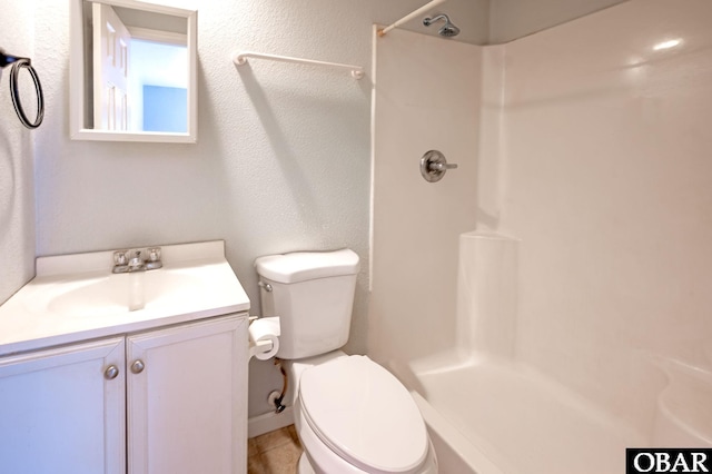 bathroom featuring toilet, a textured wall, walk in shower, and vanity