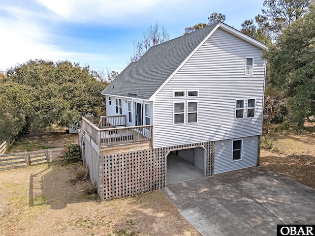 view of front of property with roof with shingles, concrete driveway, fence, a deck, and a carport