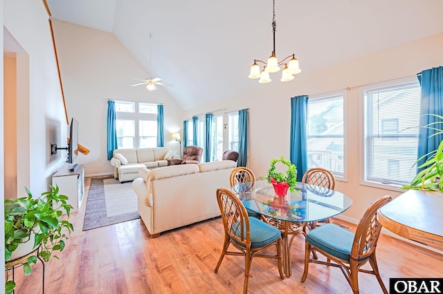 dining area featuring ceiling fan with notable chandelier, high vaulted ceiling, and light wood finished floors