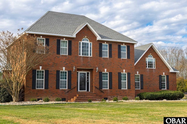 colonial house featuring brick siding, a shingled roof, entry steps, crawl space, and a front yard