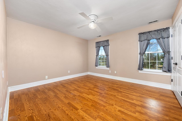 empty room featuring baseboards, wood finished floors, and plenty of natural light
