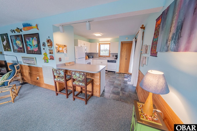 26224 Cutlass Ln Lot 27, Salvo, NC 27972 - kitchen with white appliances, a peninsula, white cabinetry, light countertops, and a kitchen bar