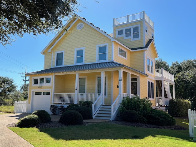 view of front facade featuring driveway, metal roof, covered porch, a standing seam roof, and a front lawn