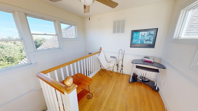 interior space featuring a ceiling fan, visible vents, plenty of natural light, and an upstairs landing