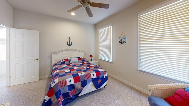 bedroom with a ceiling fan, light colored carpet, and baseboards