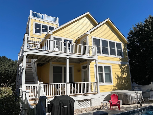 rear view of property featuring a patio, a hot tub, central AC, fence, and a balcony