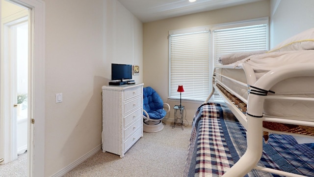 bedroom featuring light carpet and baseboards