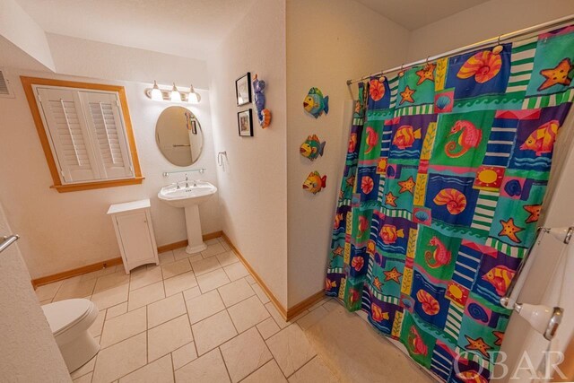 bathroom featuring tile patterned flooring, toilet, a sink, baseboards, and a shower with curtain