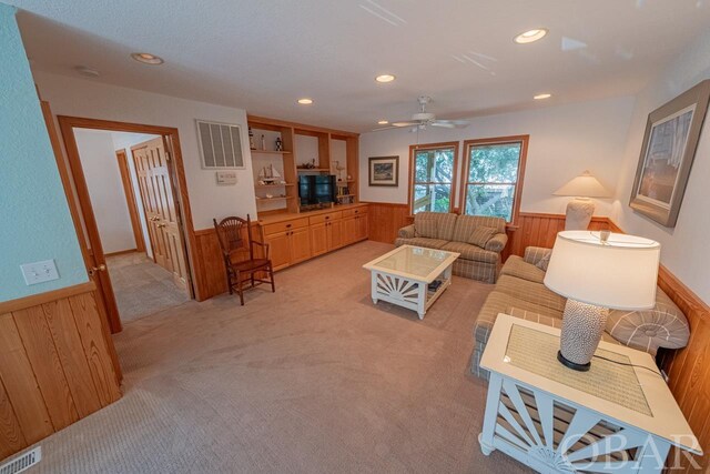 living area featuring a wainscoted wall, visible vents, and wooden walls