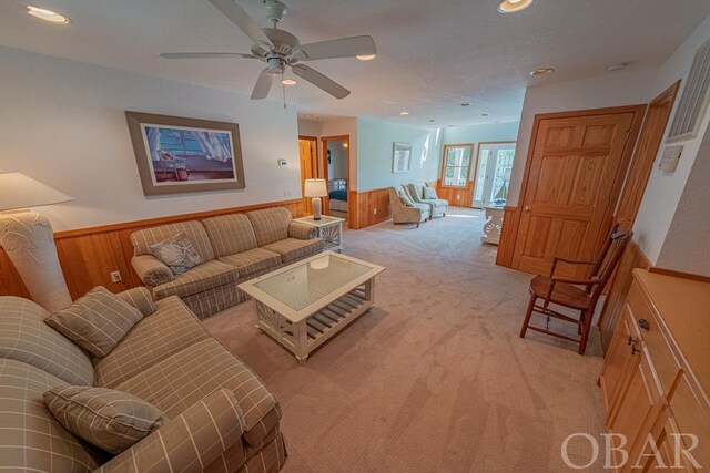 living room featuring light carpet, a wainscoted wall, recessed lighting, and wood walls