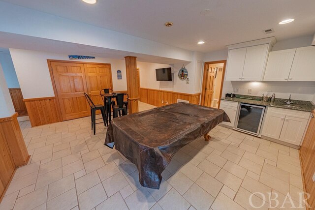 rec room with a wainscoted wall, wine cooler, pool table, wet bar, and wood walls