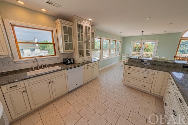 kitchen featuring visible vents, hanging light fixtures, glass insert cabinets, a sink, and dishwasher