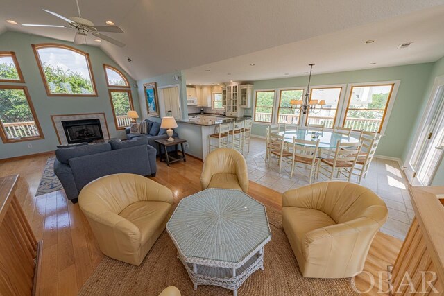 living room with visible vents, baseboards, a fireplace, high vaulted ceiling, and recessed lighting