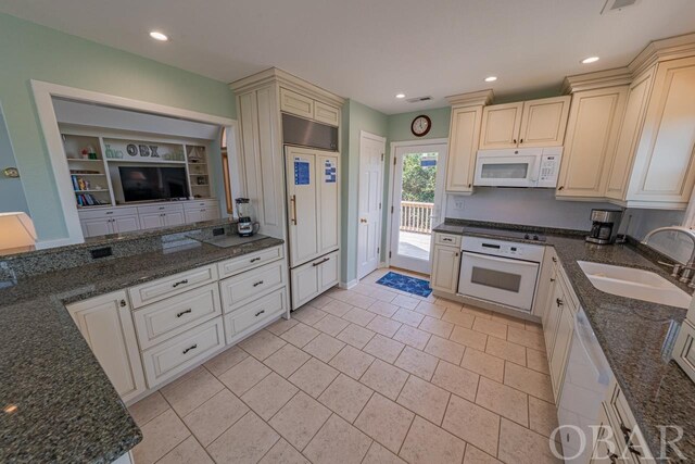 kitchen featuring white appliances, dark stone counters, a sink, and recessed lighting