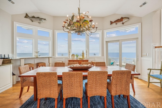 dining room with a water view, light wood-style flooring, visible vents, and lofted ceiling