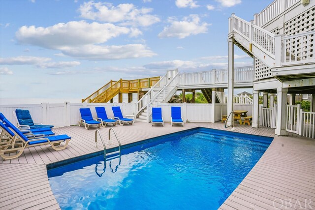 view of swimming pool featuring fence, stairway, a fenced in pool, and a wooden deck