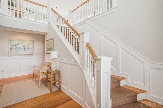 stairs featuring a decorative wall and wood finished floors