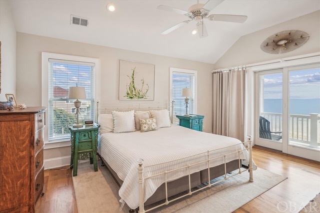 bedroom featuring visible vents, lofted ceiling, light wood-style flooring, a water view, and access to outside