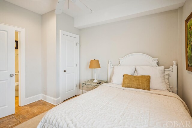 bedroom featuring ensuite bathroom, ceiling fan, light tile patterned flooring, and baseboards