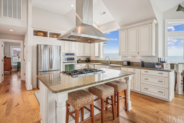 kitchen featuring a kitchen island, visible vents, appliances with stainless steel finishes, dark stone counters, and island exhaust hood