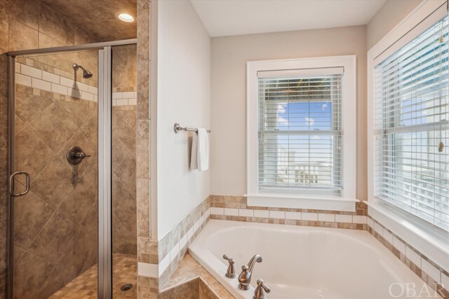 full bathroom with a wealth of natural light, a stall shower, and a bath