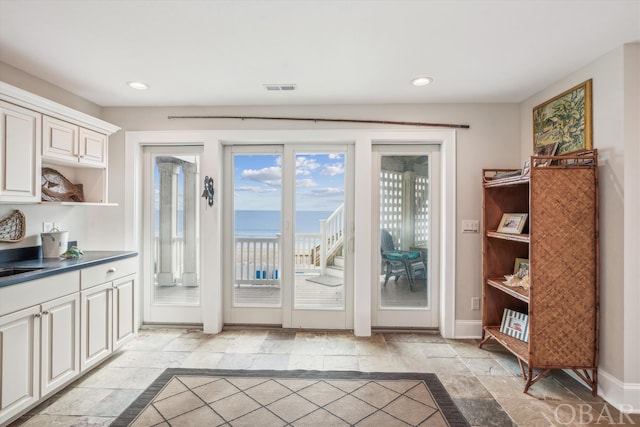 doorway featuring baseboards, visible vents, a sink, and recessed lighting