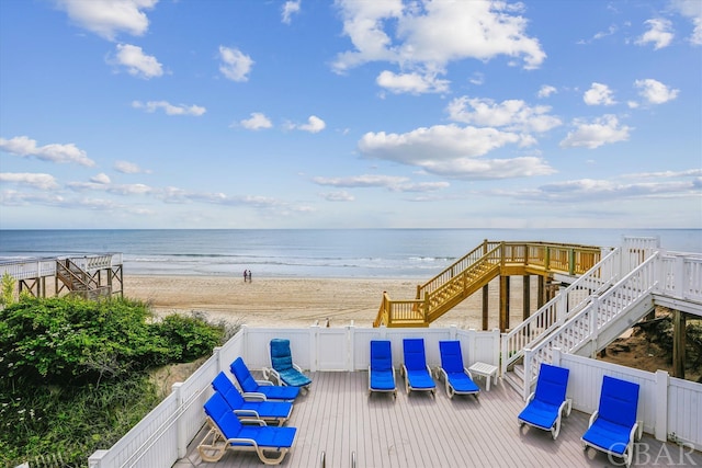 wooden terrace with a view of the beach, a water view, and stairs